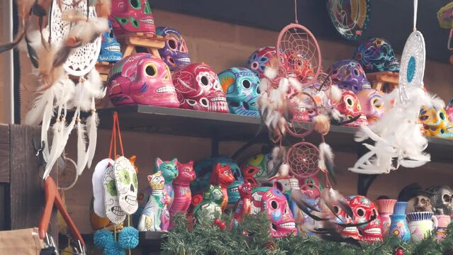 Mexican souvenirs on market stall, colorful painted skulls and dream catchers. Multicolor vivid ethnic ornaments, bazaar or marketplace. Ceramic crafted death symbol for sale on counter. Day of Dead.