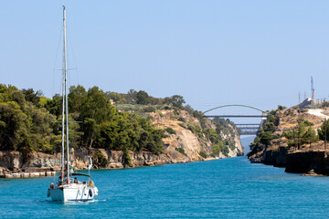 sailing boat passing Corinth Canal,  with the bridge on top connecting mainland Greece with...