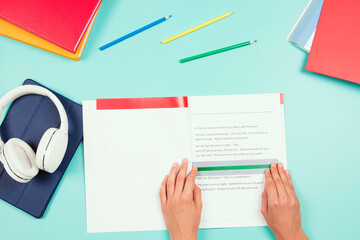 Child doing homework, reading book using colored rulers overlays strips. Top view to desk with books and school supplies. Education, learning disability, reading difficulties