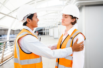 Supervisor touching worker shoulder consoling after accident in construction site at middle...