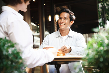 Fototapeta na wymiar Smiling handsome man talking to girlfriend at meeting or romantic date in bakery cafe, happy pretty charming girl having conversation with boyfriend. concept of couples and dating