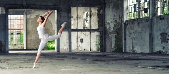 Ballerina in white jumping and dancing in a dusty abandoned building