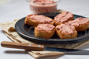 Homemade beef liver pate in a glass jar and baguette slices with pate