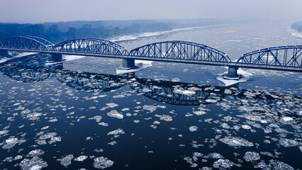 Snowy bridge and river with floe in winter.