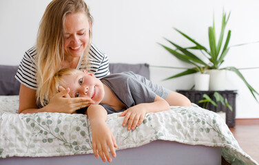 lovely emotional scene with happy mother and son in bedroom
