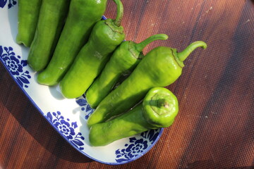 Some tiny cherry tomatoes and green peppers in white plates on wooden concept.