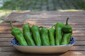 Some tiny cherry tomatoes and green peppers in white plates on wooden concept.