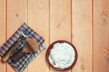 Flat lay with natural shaving accessories, razor blade and brush on the wooden table. Barbershop, skincare and washing backgrounds