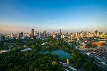 Naklejka premium Modern office building and hotel with tree park in city of Bangkok against blue sky cloud
