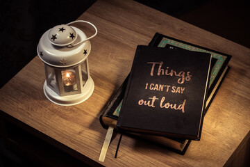 A diary with an inspirational quote lying on the table next to a candle.