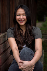 Casual lifestyle outdoor portrait of a beautiful happy young woman with long brown hair sitting...