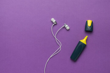 Yellow marker and white headphones on a purple background.