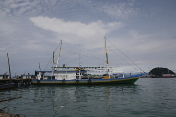 Fototapeta premium The boat that will sail, is leaning on the Indonesian pier, on a sunny day.