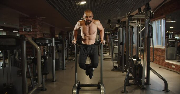 Handsome sportsman bodybuilder doing pull-up exercises in the gym. 