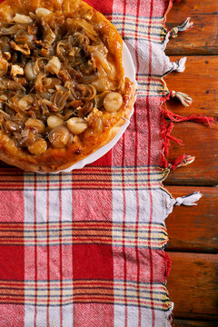 Onion Tarte Tatin With Potatoes And Feta Cheese Stands On A Plate On The Table. High Quality Photo