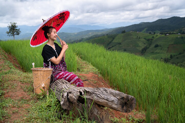 Woman hill tribe holding red umbrella with landscape rice terrace background	