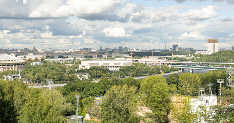 Panorama of Moscow, Luzhniki sports stadium, green area with trees and bushes, cable car, Moskva River, bridge for cars and metro.