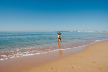 BEAUTIFUL GIRL WALKING AND ENJOYING THE SUN AND THE BEACH ON HER VACATION AND GETTING INTO THE OCEAN AND VERY HAPPY AMD SMILLING