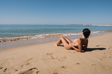 Fototapeta na wymiar BEAUTIFUL GIRL LOOKING AT THE HORIZON ON THE BEACH ON VACATION AND HAPPILY MEDITATING