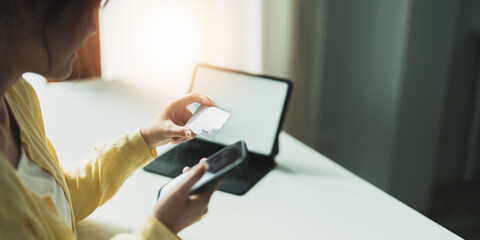 Close up of girl hold bank credit card, shopping online using mobile phone, buying goods or ordering online, entering bank accounts and details in online banking offer.