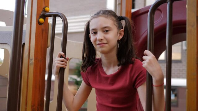 Portrait of a cheerful girl sitting on the playground.