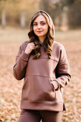 Young woman in hooded sweatshirt in an autumn park. Sunny weather. Fall season.