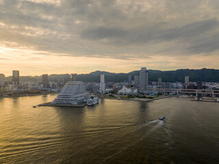 Small boat passes luxury cruise ship docked at waterfront hotel as sun sets