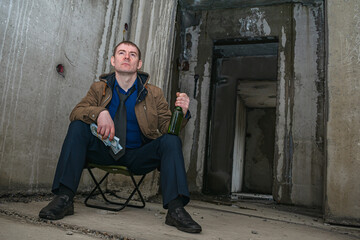 Ruined businessman in desperation gets drunk with alcohol in a ruined building