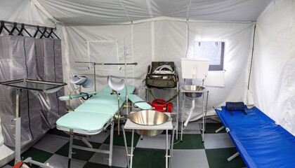 Tent operating room. Equipment for medical operating inside tent. Medical couches inside tent hospital. Location for operations. Rapidly erected hospital. Operating room of prefabricated room