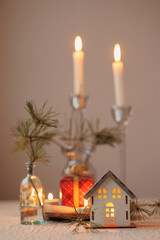 Christmas tree and a candlestick in the form of a house, soft selective focus. a cozy miniature layout of the house. decorations for Christmas with candles, confetti and ribbons, holidays. give gifts