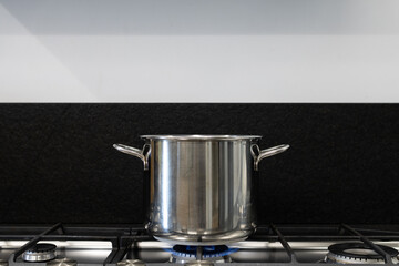 Steel pot on the fire of a gas stove in the kitchen. Concept for the global European problem of natural gas supply.