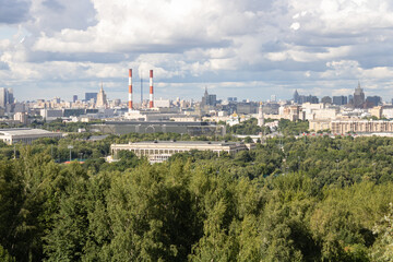 Panorama of Moscow, green area with trees and bushes, buildings, chimneys, TV tower Ostankino. Cloudy sky, summer day.