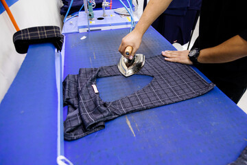 Tailor ironing clothes in tailoring shop