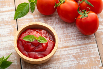 Tomato sauce with basil leaf in a wooden bowl and red tomatoes fruit