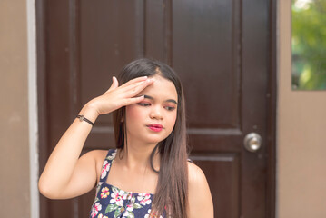 A young teenager is outside her home experiencing a headache due to the afternoon heat.