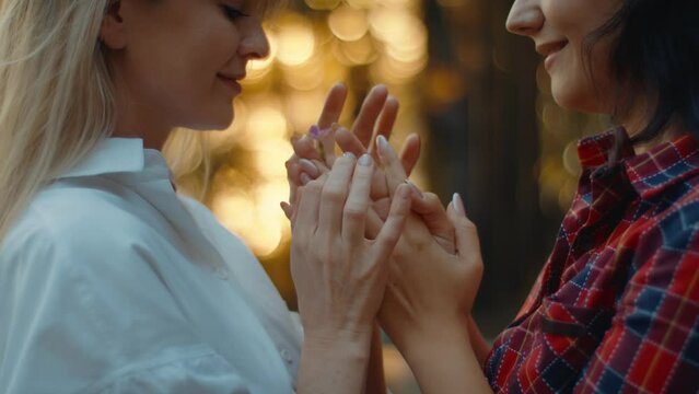 Close-up of a lesbian couple holding hands and looking at each other lovingly. Homosexual couple of two women