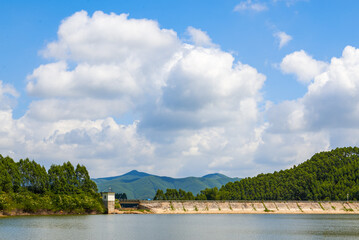 View of blue sky, white clouds and green hills and forest at outdoor reservoir