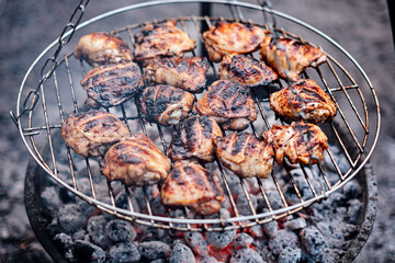 Grilled Chicken Thighs on charcoal grill outdoors. BBQ Chicken. Frilling bone-in chicken legs,...