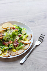 Caesar salad on a white plate. Yellow mustard sauce, quail eggs, herbs, croutons. Front view. Copy space