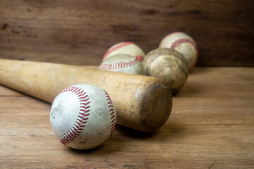 Close up old baseball and wooden baseball bat on a woodeb table. select focus.