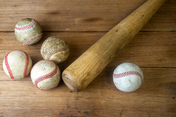 Close up old baseball and wooden baseball bat on a woodeb table. select focus.
