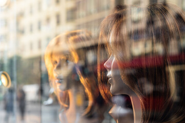 Fototapeta na wymiar Female mannequin heads with wigs, behind a wig shop window