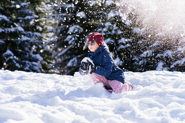 Fototapeta na wymiar Child playing in snow on winter vacation. Snowball fight. Kid having fun in snowy forest. Family outdoors activities on Christmas holidays. Authentic lifestyle moment
