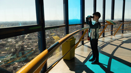 Menino de binóculo observa a cidade de Curitiba em sua Torre Panorâmica.