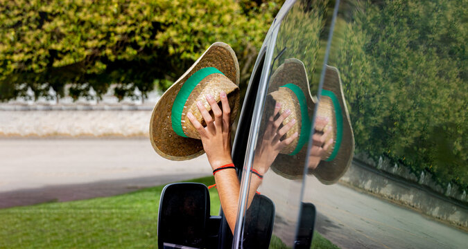 person waving out of the car window with a straw hat with copy space