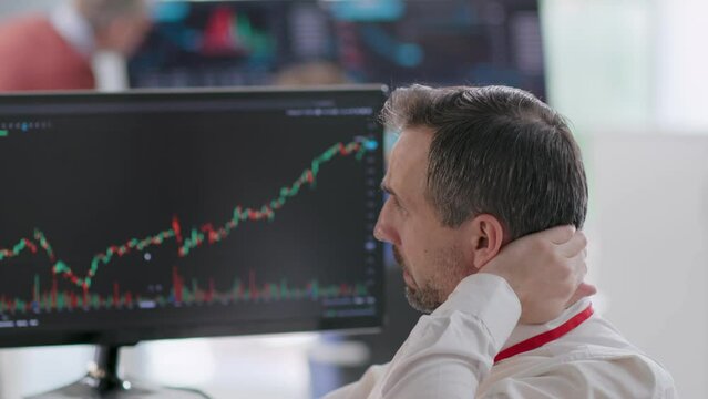Mature financial analyst looking at computer with graphs and feeling frustrated