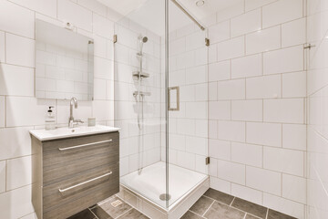 Sinks with mirrors and shower box with glass door in modern bathroom with white tiled walls - obrazy, fototapety, plakaty