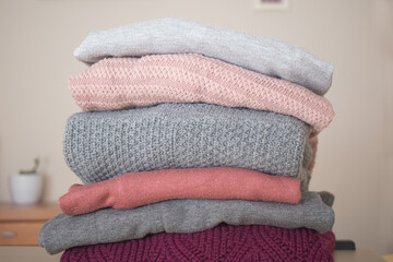 Pile of gray and pink wool sweaters in a room