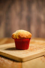 Cupcake isolated on wooden table. Cupcake in red paper mold.