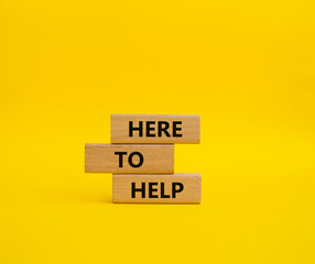 Here to help symbol. Wooden blocks with words Here to help. Beautiful yellow background. Business and Here to help concept. Copy space.